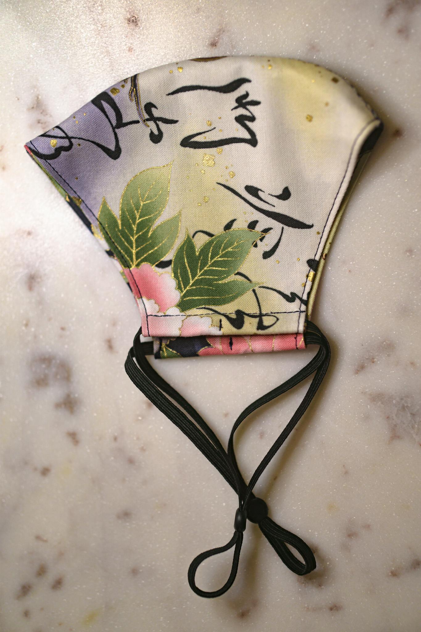 Floral face mask with ties on a marble background, showcasing style and safety.